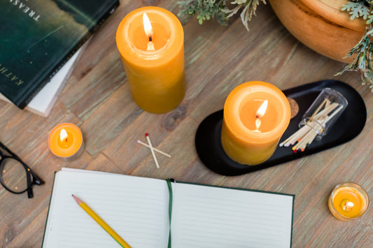Bluecorn raw beeswax pillar candles and tea lights beside a journal and matches