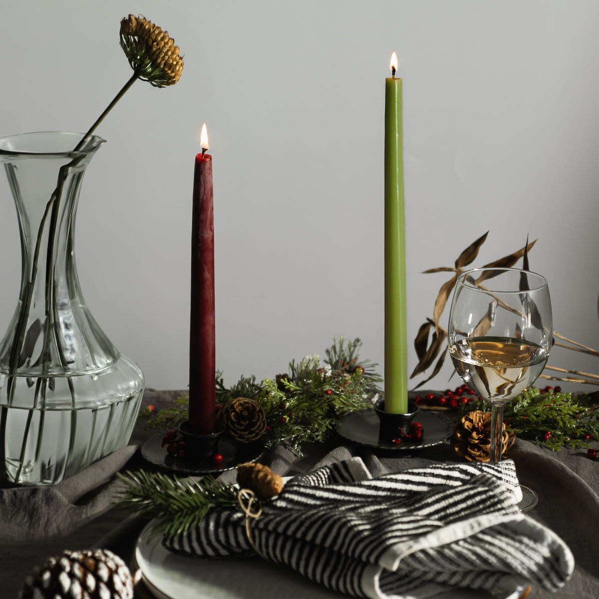 dark red beeswax taper candles next to a light green beeswax taper candle for a modern holiday table