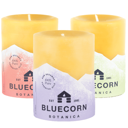 3 scented bluecorn beeswax scented pillar candles with Green (Eucalyptus & Orange), Purple (Lavender) and Orange (Tangerine & Geranium) labels that say Bluecorn Botanica with a white background