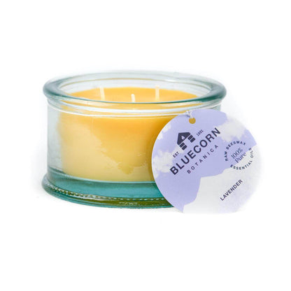 Bluecorn Botanica 100% Pure Beeswax scented candle - Lavender 10oz 3-Wick Glass Candle. Wax is golden in color and glass is clear colored, with a white back drop. Features purple Bluecorn Botanica hang tag printed on 100% recyled paper with Bluecorn name and logo. Burn Time: 18 hours.  Made with 100% Pure Beeswax, 100% Pure Essentail Oils and a 100% pure cotton wick, no lead. Candles are paraffin free, clean burning and non-toxic. 
