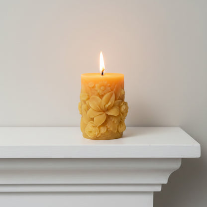 scented sculpted beeswax pillar candle burning on fireplace mantel