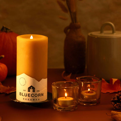 Bluecorn Beeswax raw pillar burning alongside tea light candles in whiskey votive holders with fall decor background