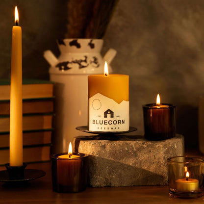 Hand-dipped beeswax taper candles and vibrant beeswax pillar candle in a cozy setting.