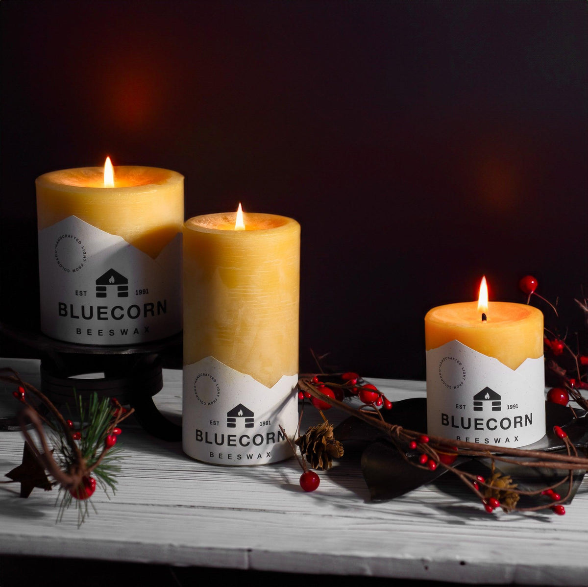 Close-up of lit 3 inch beeswax pillar candles with holiday decor