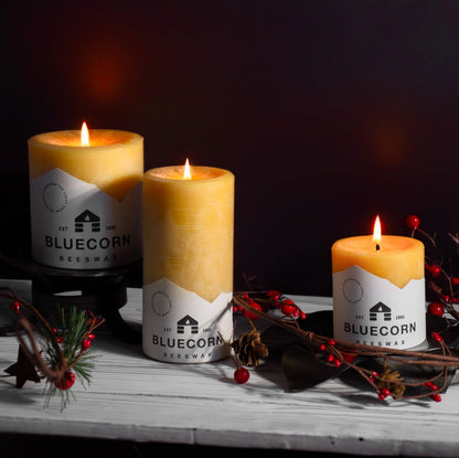 Close-up of lit 3 inch beeswax pillar candles with holiday decor