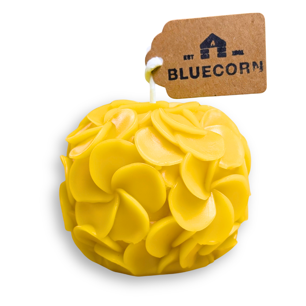 Hydrangea shaped candle in yellow beeswax, featuring pinwheel petals and a tag from Bluecorn.