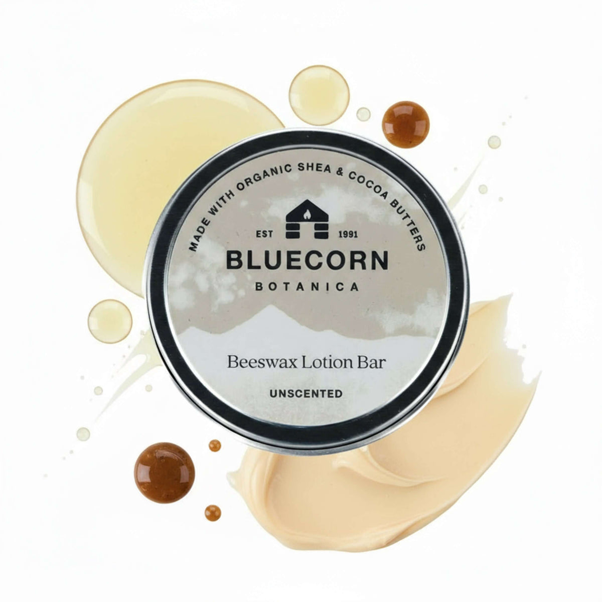 Bluecorn Botanica Beeswax Lotion Bar in Unscented. Made with Organic Shea Butter, Organic Cocoa Butter, Avocado Oil, Apricot Oil, Cappings Beeswax, Essential Oils. Using the warmth of your hands, these solids bars will turn into lotions. Can be used all over the body and come in a convenient tin. Features grey Bluecorn Botanica Label on aluminum tin with opened lid showing lotion bar. Lotion bar is cream in color and features Bluecorn cabin.