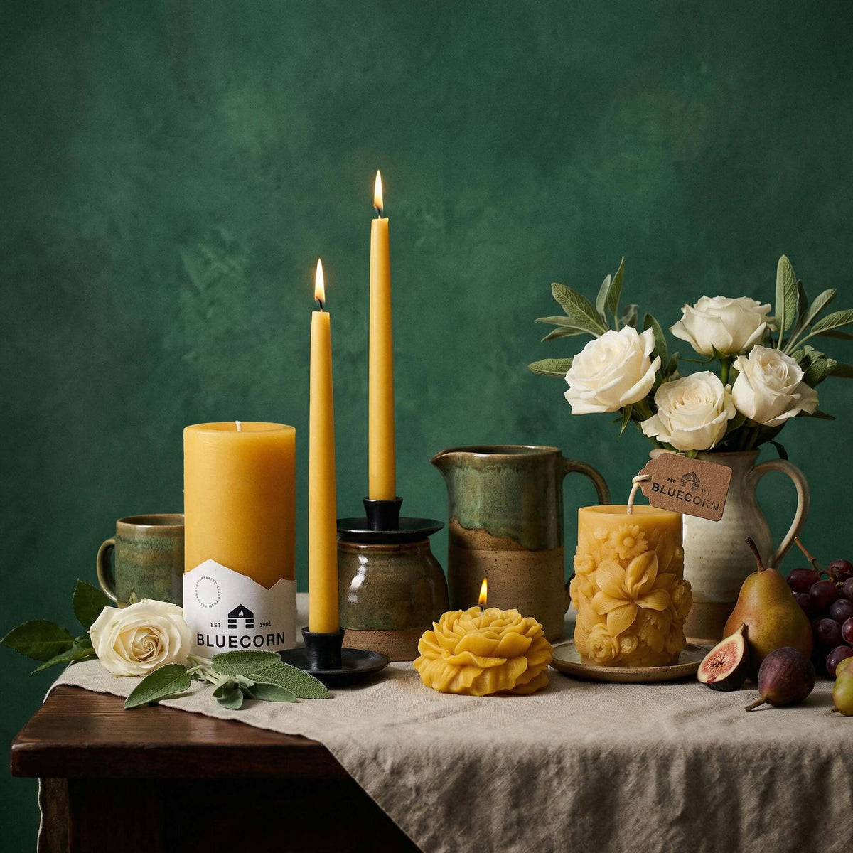 Beeswax taper candles displayed alongside various decorative candles and floral arrangements on a rustic table.