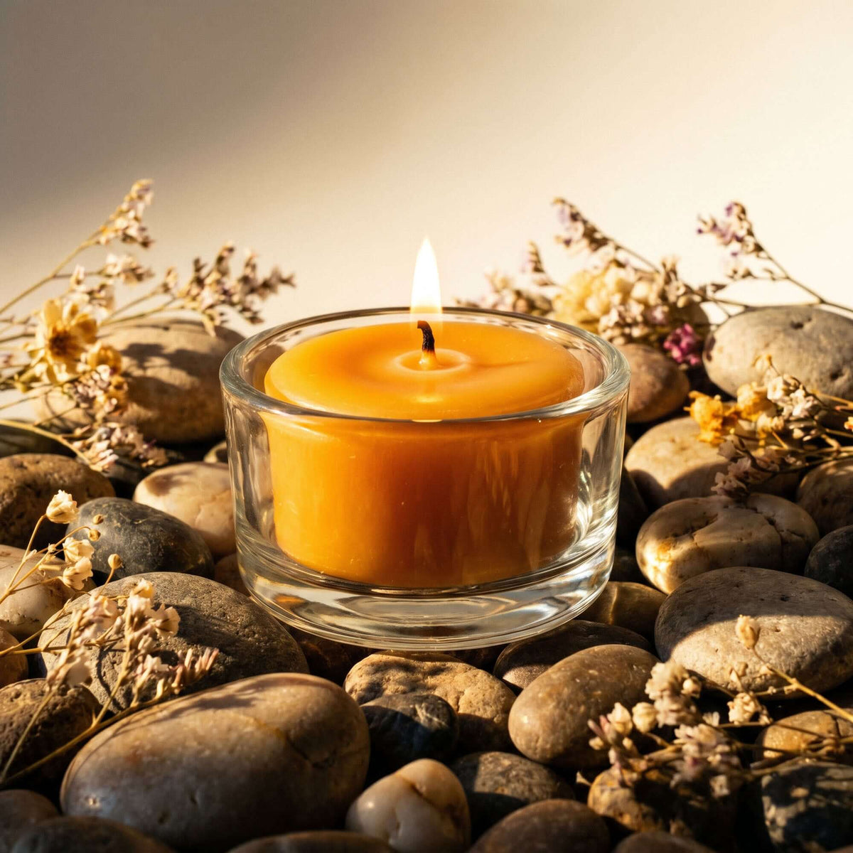 Pure beeswax tea light candle burning in clear glass refillable holder 
