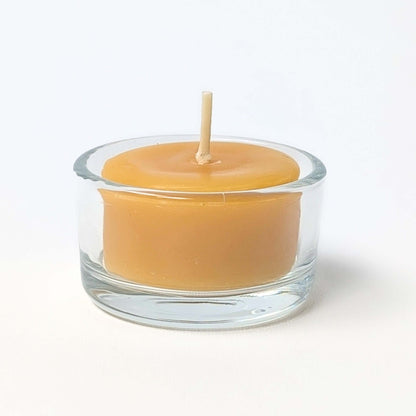 Beeswax candle in a clear glass holder on a white background