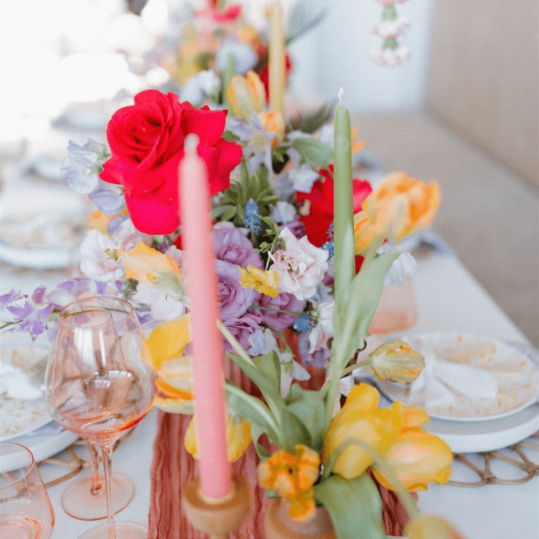 Spring candle set with light pink taper candle from bluecorn candles in front of a floral spring table with green candlesticks