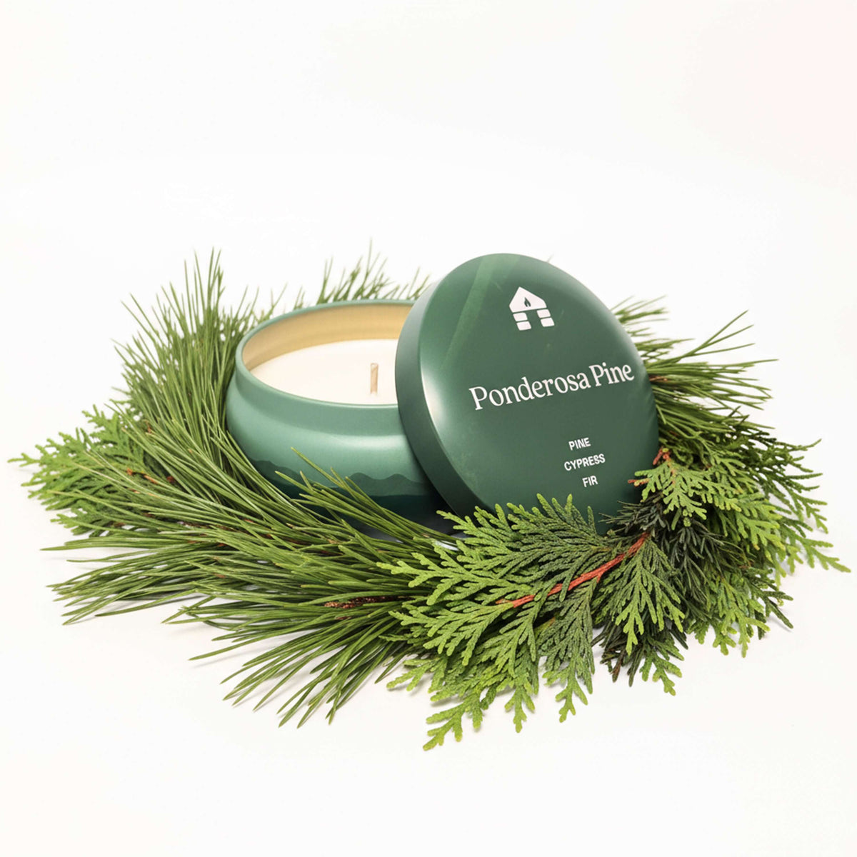 Bluecorn Aromática 8oz Ponderosa Pine scented candle tin in a bed of pine needles with a white background
