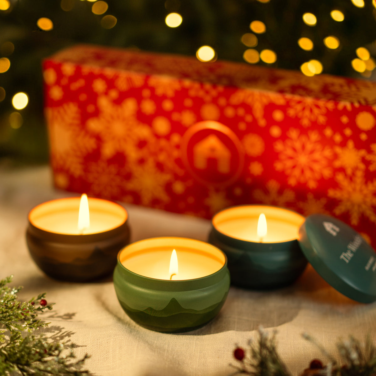 Scented candle gift set featuring three vibrant 8oz candle tins in a festive red box with gold and snowflake design.